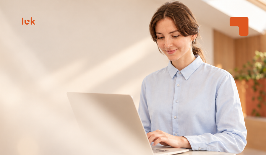 Mujer de camisa celeste trabajando en su computador en una oficina luminosa